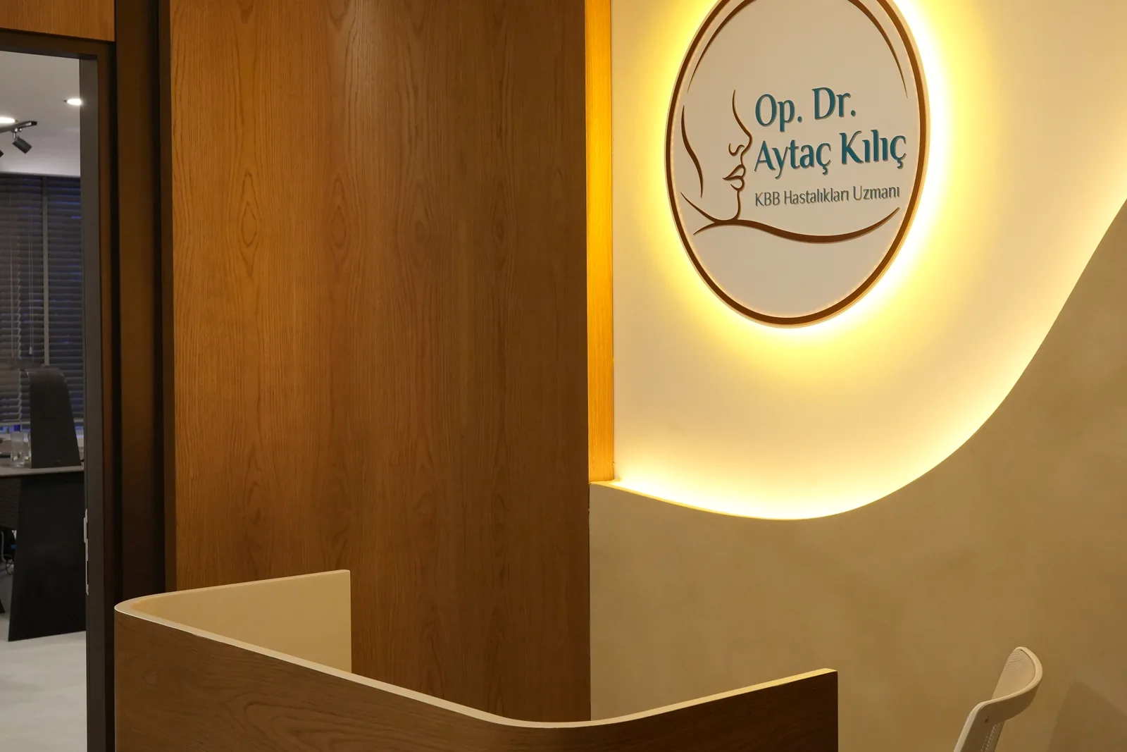 Reception desk of the practice with the illuminated clinic logo behind it